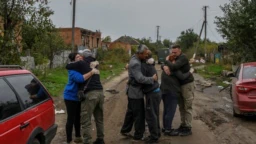 Соседи обнимают друг друга после возвращения в село Каменка Харьковской области, освобожденное от российских войск. 2 октября 2022 года